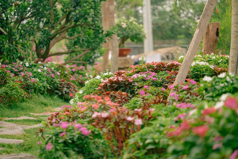 A serene garden path lined with vibrant flowers under lush green trees, perfect for a tranquil walk.